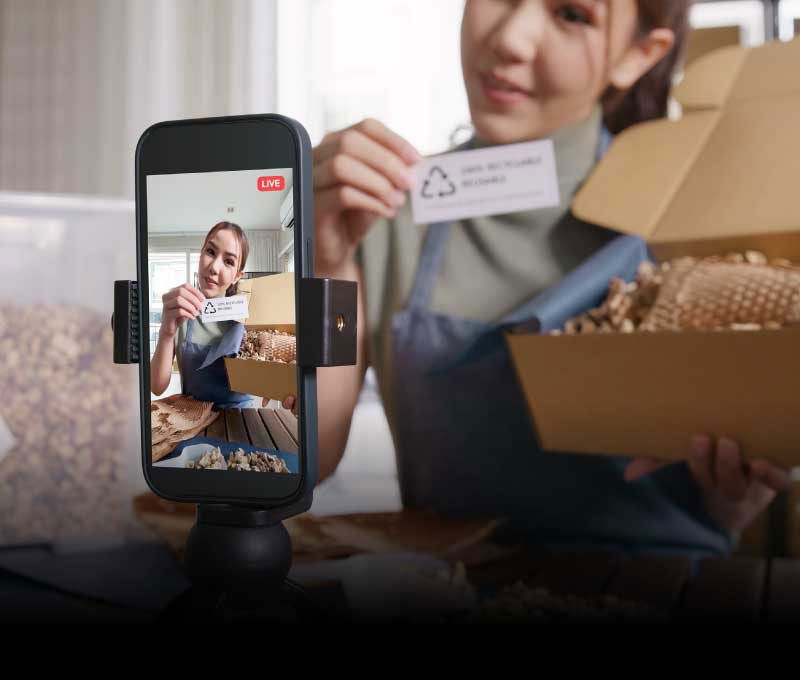 A female influencer is showcasing a product while streaming her presentation live on a mobile phone.
